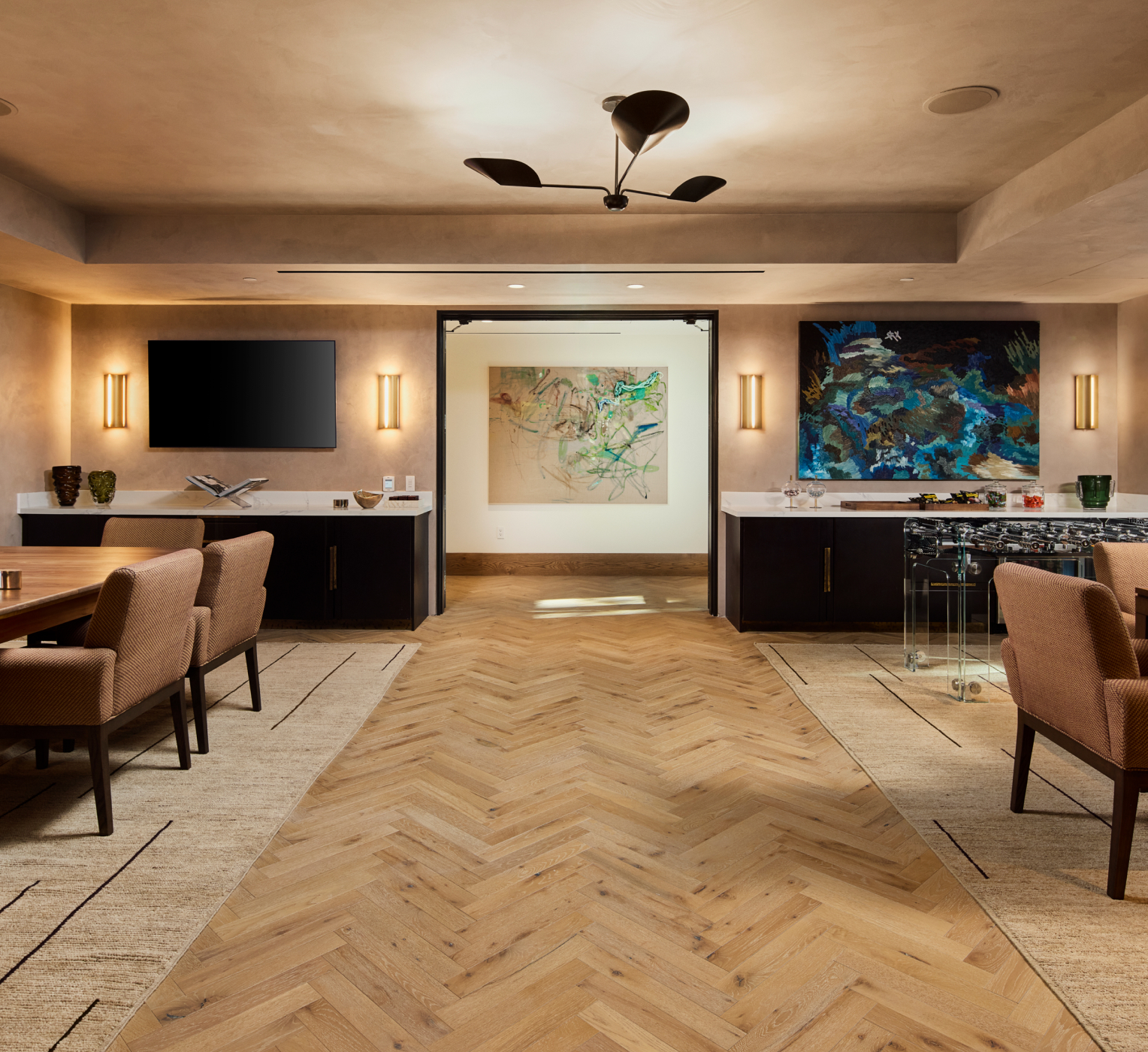 Elegant community space with modern lighting, artwork, and herringbone wood flooring