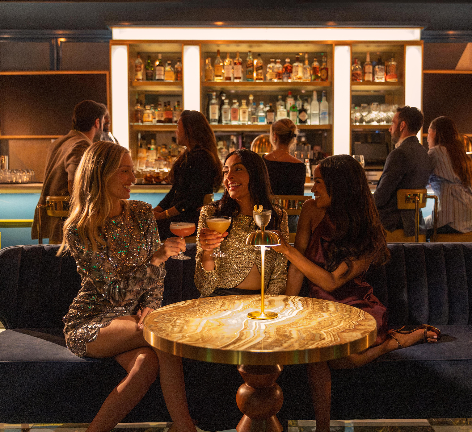 Friends enjoying cocktails at a stylish hotel bar with warm ambient lighting