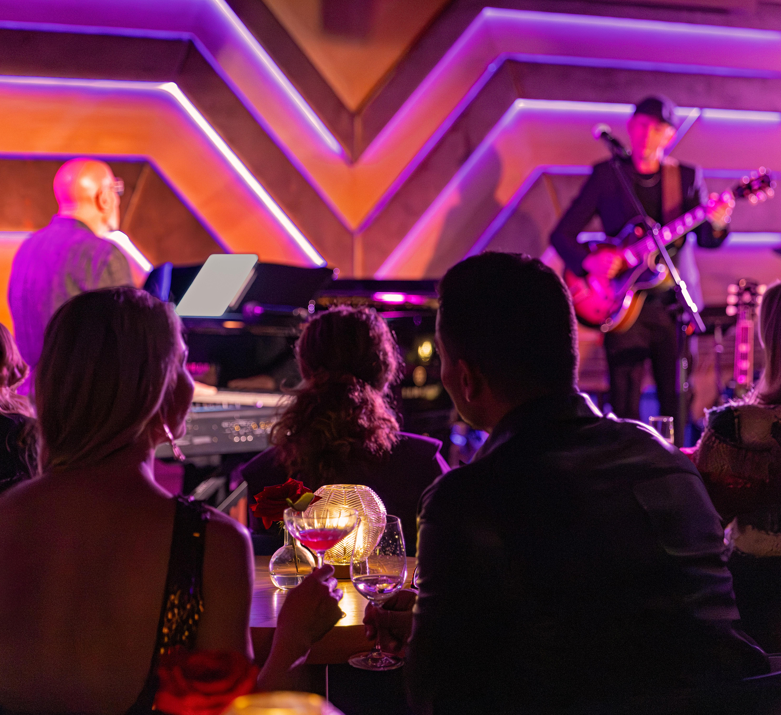 Live music performance at an intimate lounge with guests enjoying drinks and neon lighting