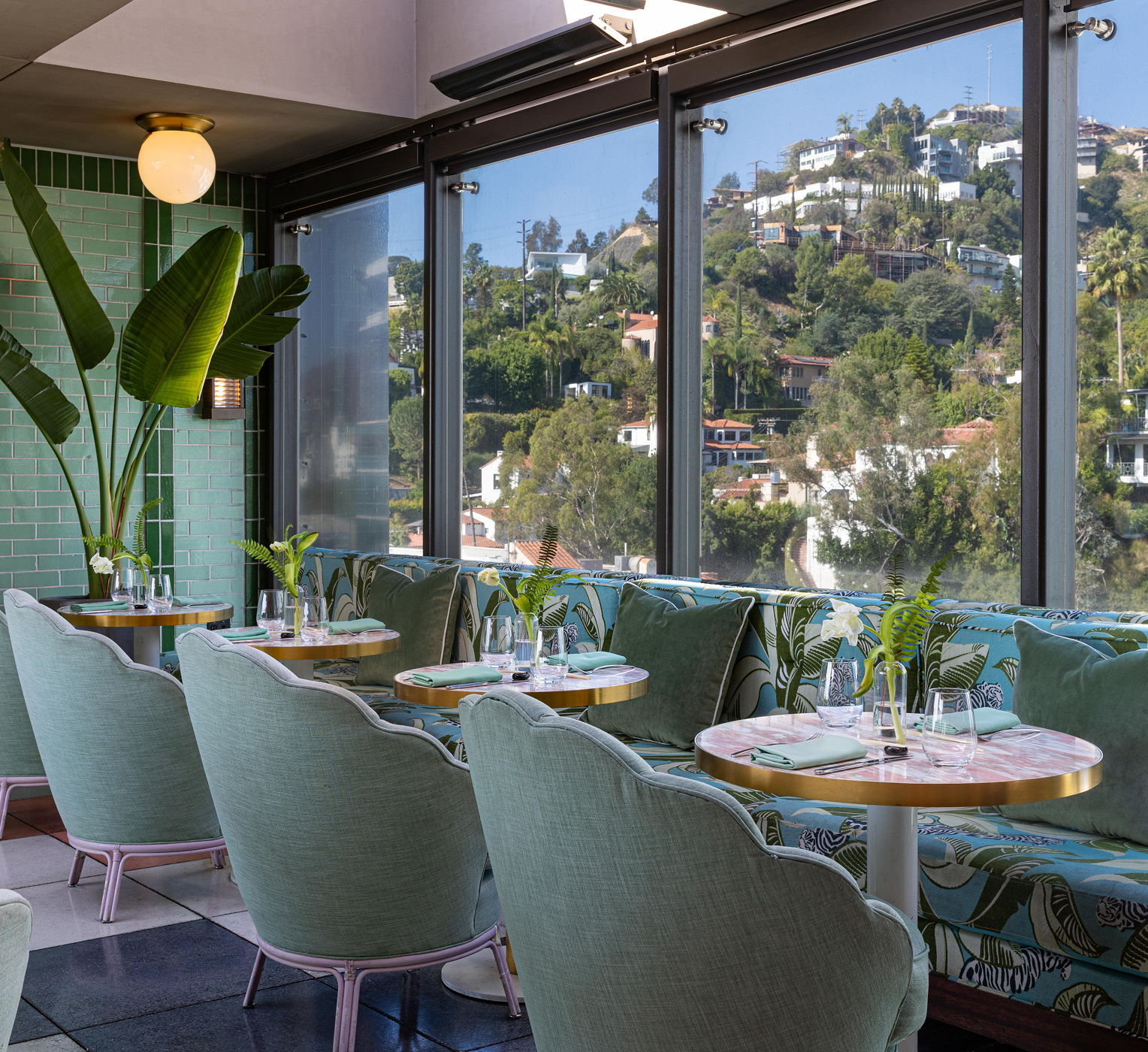Bright Merois restaurant interior with green velvet chairs and hillside views through large windows